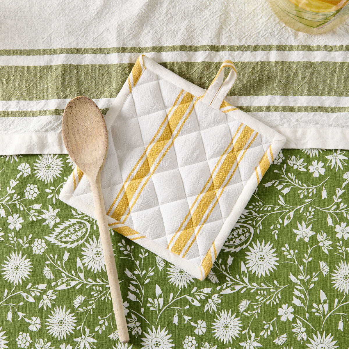manique jaune et cuillère en bois sur nappe fleurie #Couleur_JAUNE