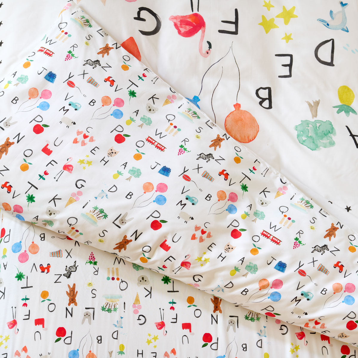 Zoom sur l’imprimé : lettres et motifs colorés façon aquarelle